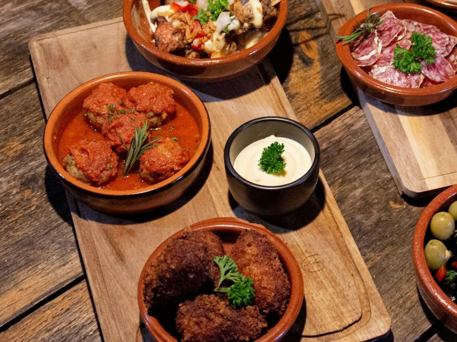 Tapas dishes on a candlelit wooden table.